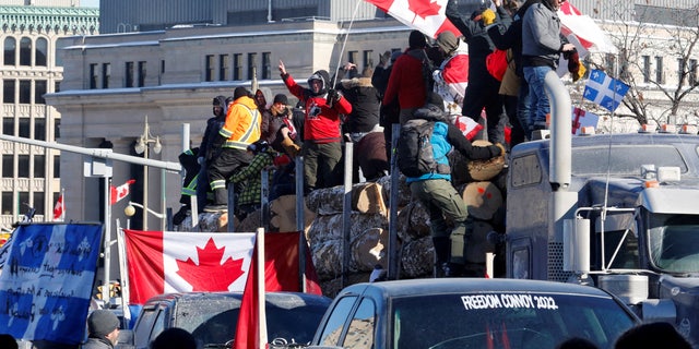 PHOTO DE DOSSIER: Des manifestants se tiennent sur une remorque transportant des bûches alors que des chauffeurs de camion et des partisans participent à un convoi pour protester contre les mandats d'un vaccin contre le coronavirus (COVID-19) pour les chauffeurs de camion transfrontaliers à Ottawa, Ontario, Canada, le 29 janvier 2022. REUTERS/PATRICK DOYLE/FICHIER Photo