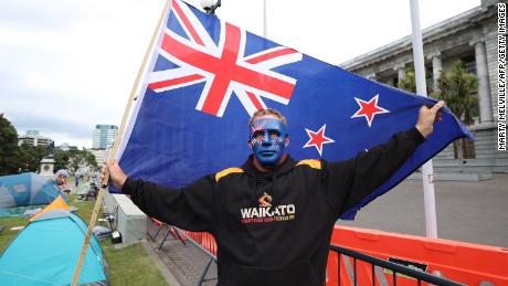 Un manifestant tient un drapeau néo-zélandais debout devant les bâtiments du Parlement le quatrième jour des manifestations contre les restrictions de Covid-19 à Wellington le 11 février.