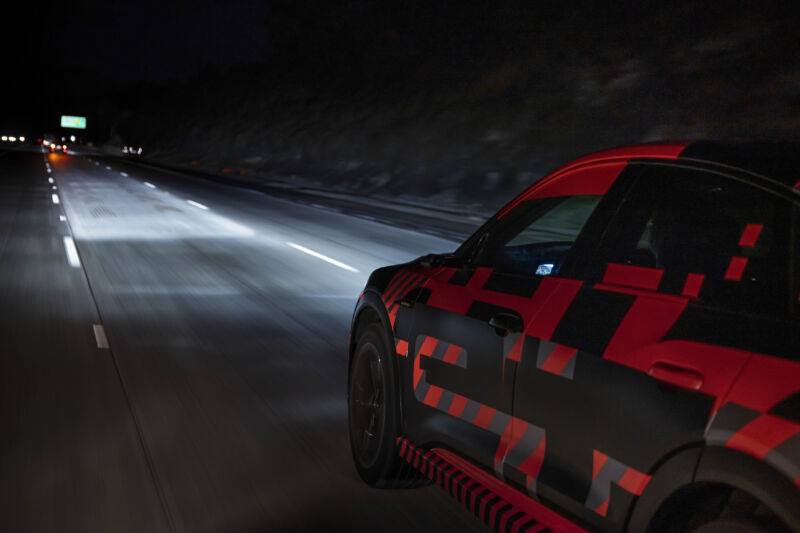 Un prototype de l'Audi e-tron sur l'autoroute en Europe éclaire son chemin avec des phares adaptatifs. 